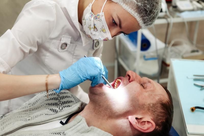 A man is getting his teeth examined by a female dentist.