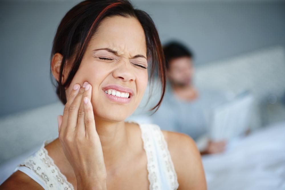 A woman is holding her face has a bad toothache