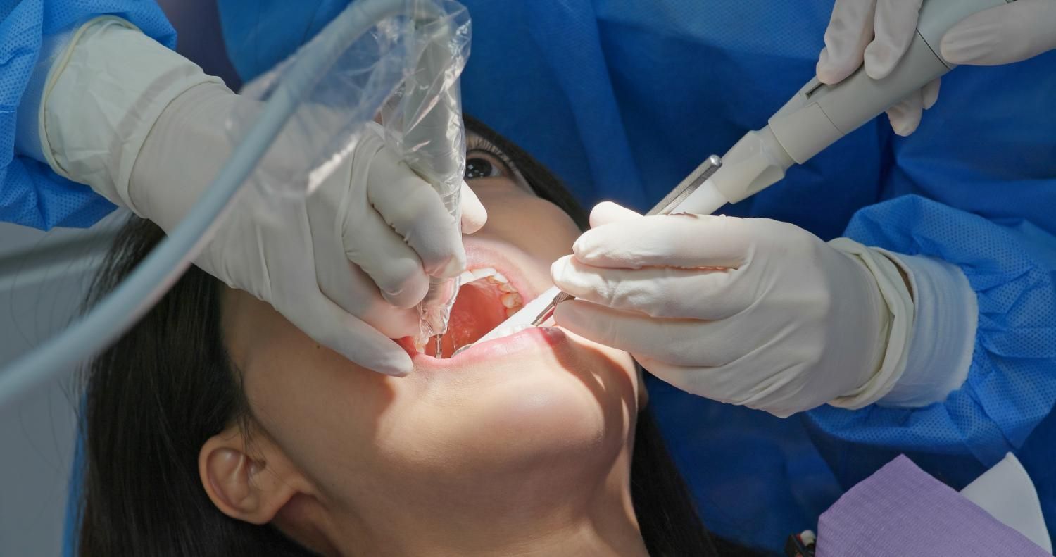 A woman is getting her teeth examined for exposed roots by a dentist