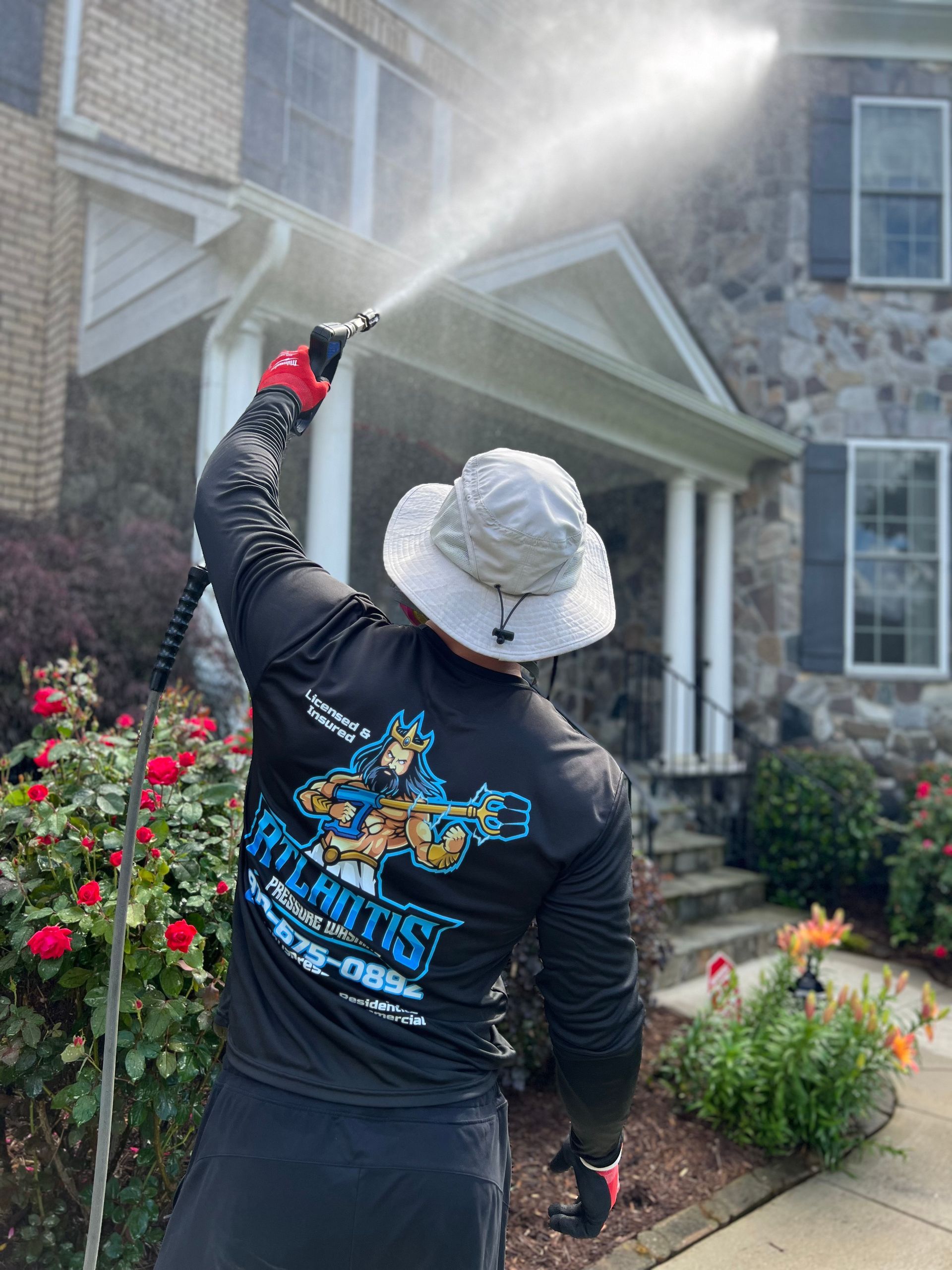 A man is cleaning a house with a high pressure washer.