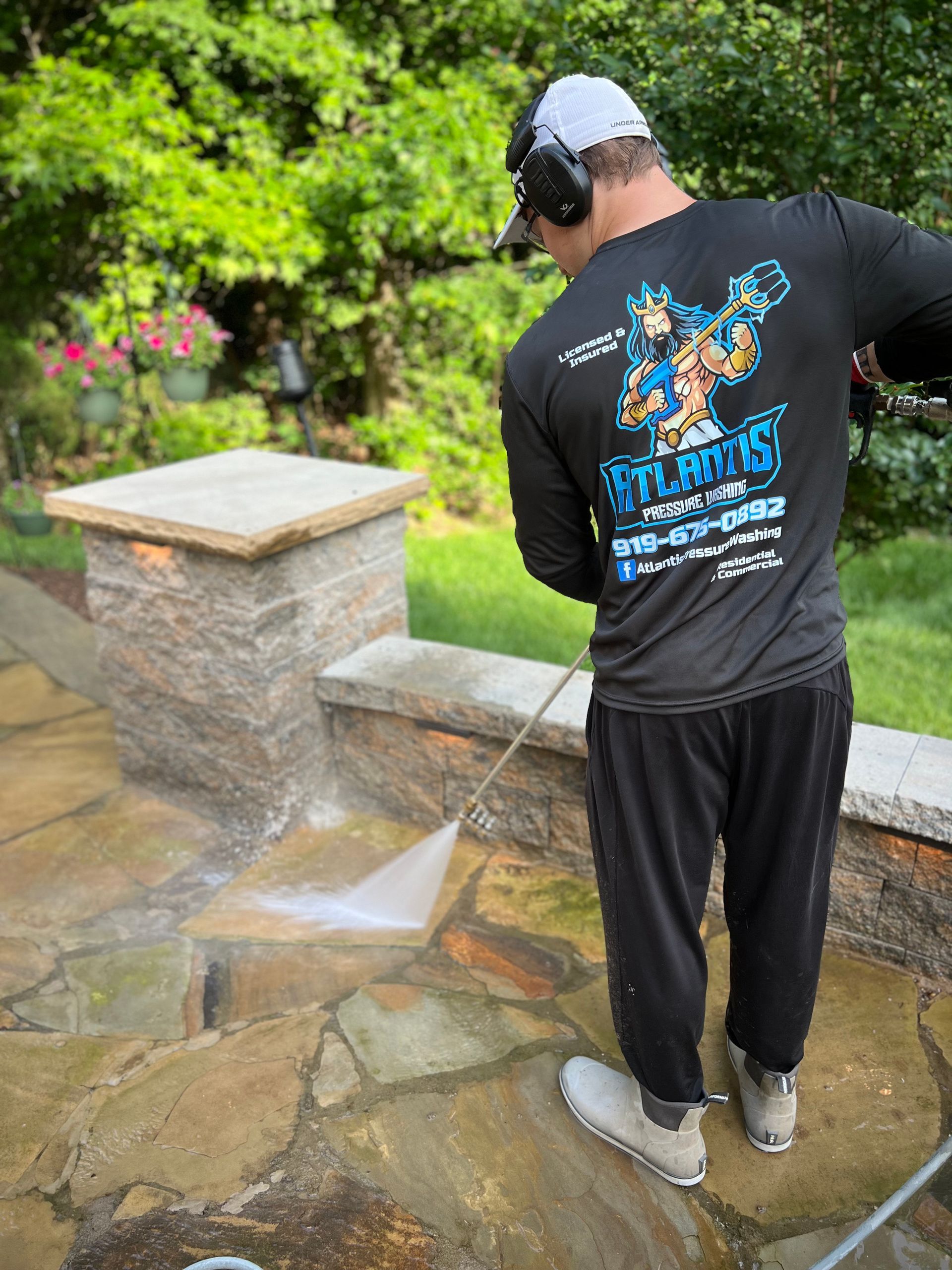 A man is cleaning a stone patio with a high pressure washer.