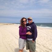 A man and a woman are posing for a picture on the beach