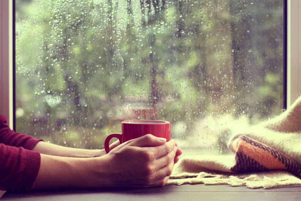 person holding coffee with rain outside