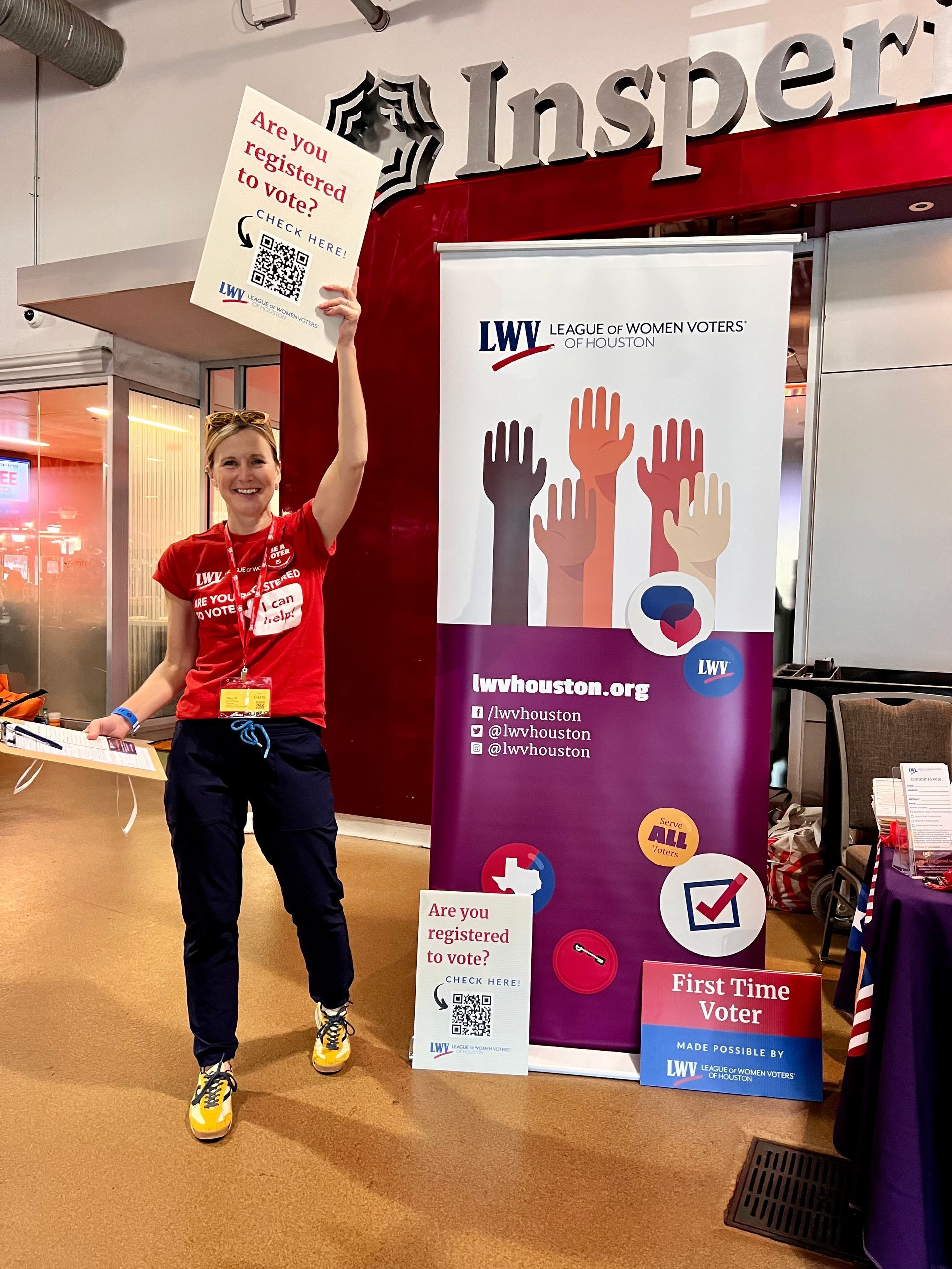 A woman is holding a sign in front of a sign that says inspector.