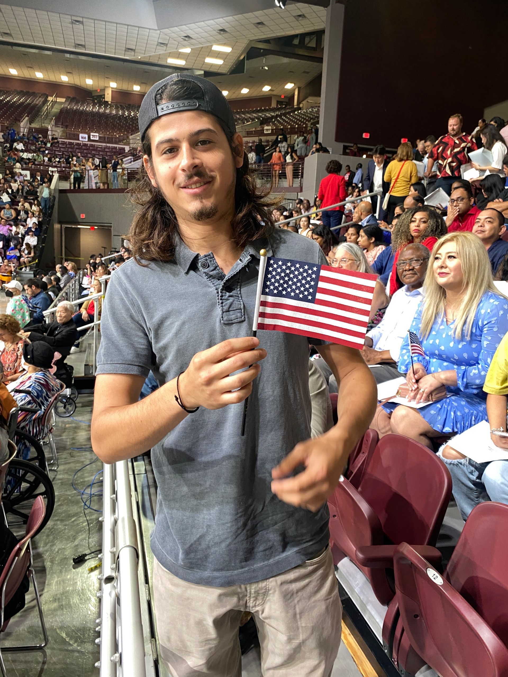 A man is holding an american flag in a stadium.