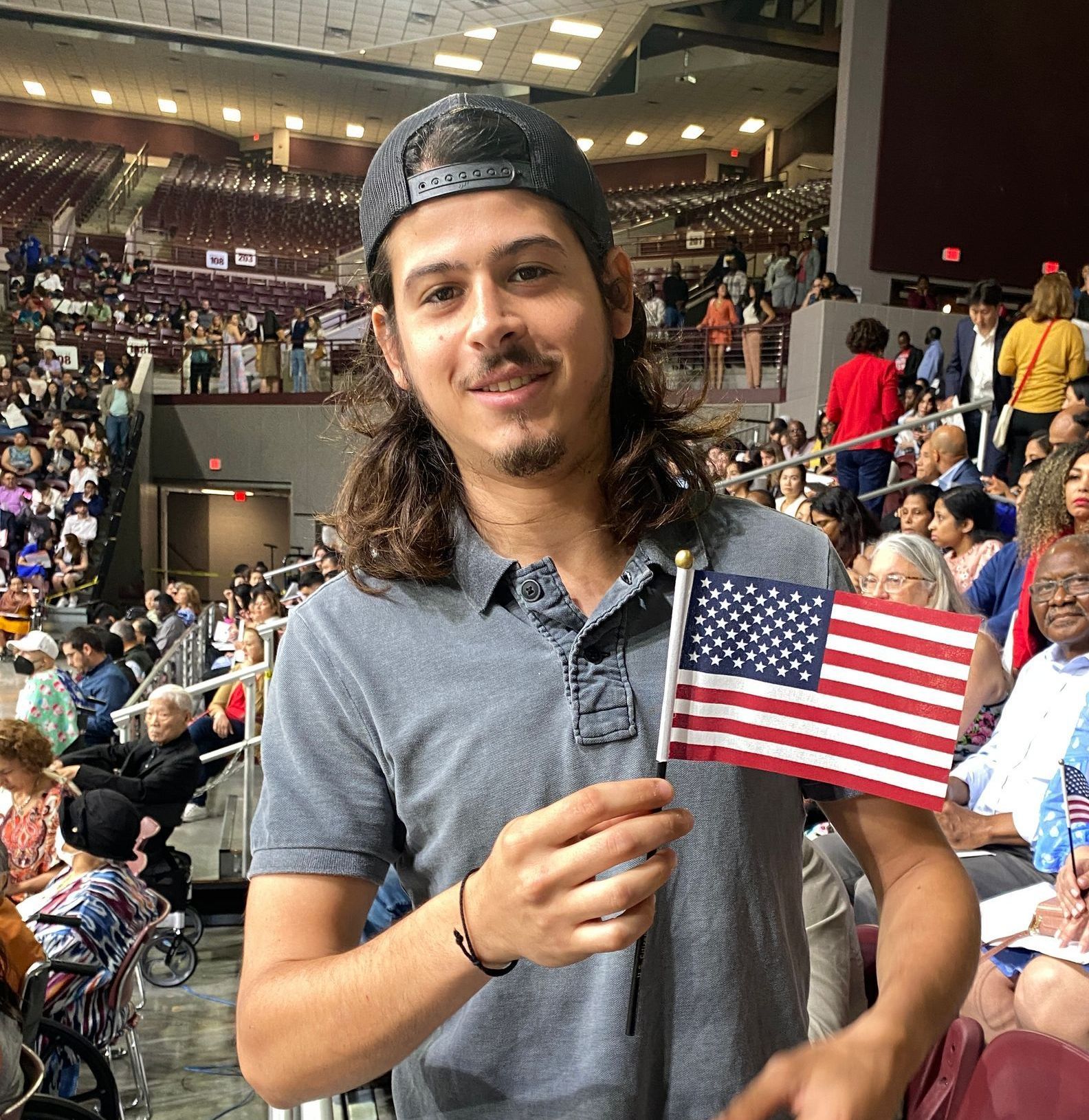 A man is holding an american flag in front of a crowd of people.