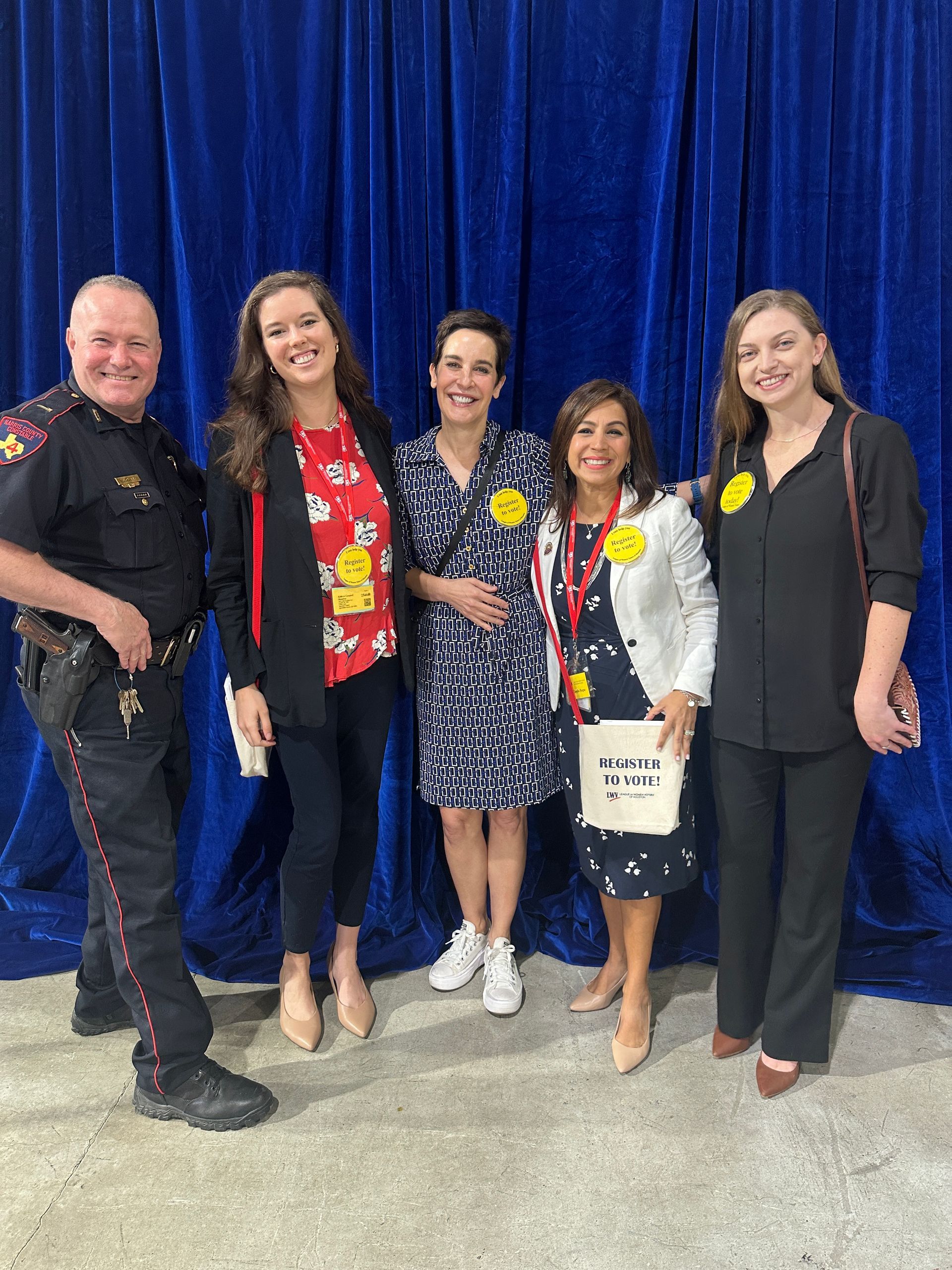 A group of people are posing for a picture in front of a blue curtain.