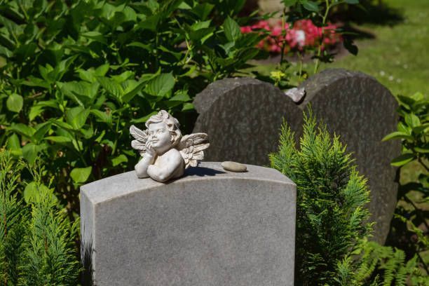 A statue of an angel is sitting on top of a grave in a cemetery.