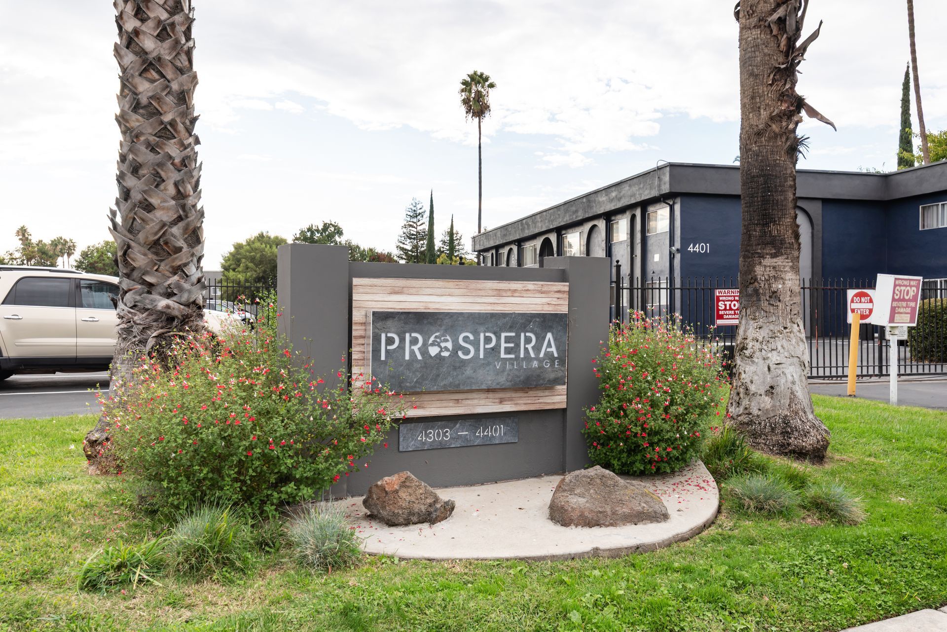 Sign for Prospera apartments with landscaping and a building in the background.