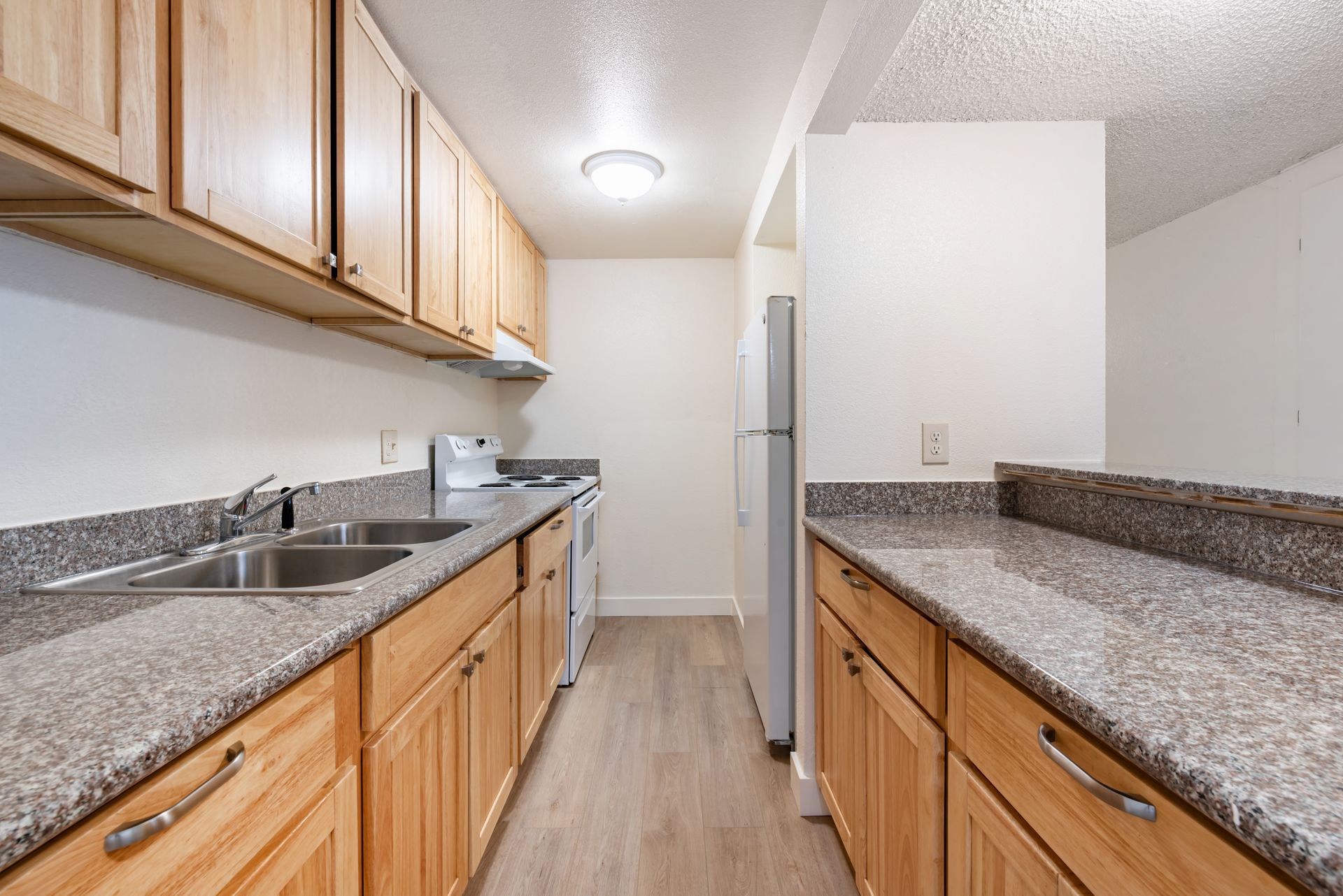 Kitchen with wood cabinets, gray countertops, and stainless steel sink and appliances.