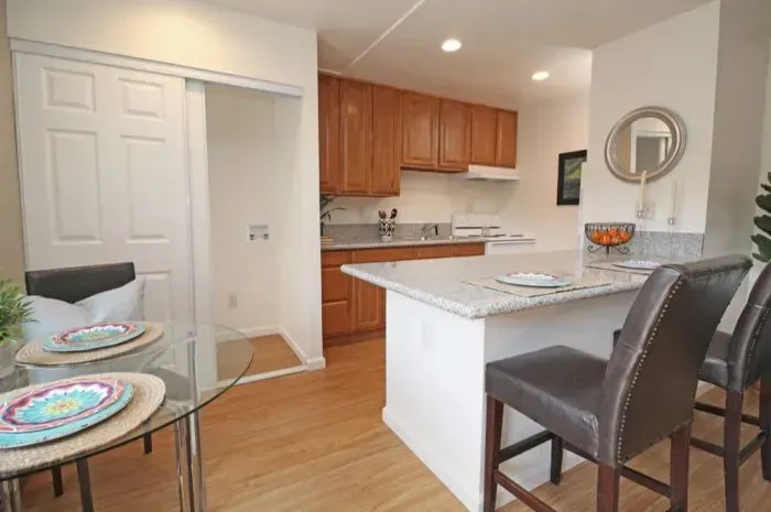Kitchen with light wood cabinets, granite countertops, and breakfast bar with bar stools.