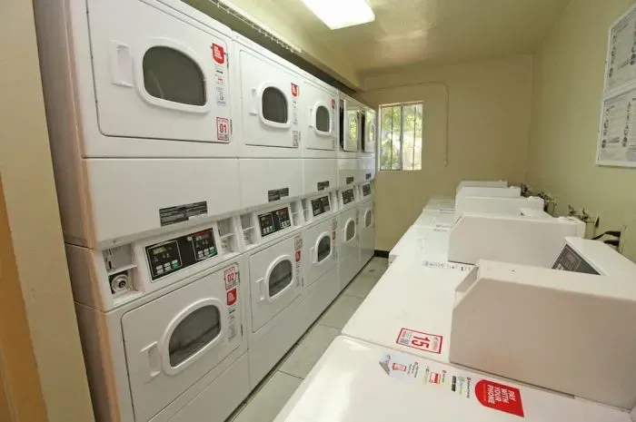 Laundry room with multiple stacked dryers and washers.