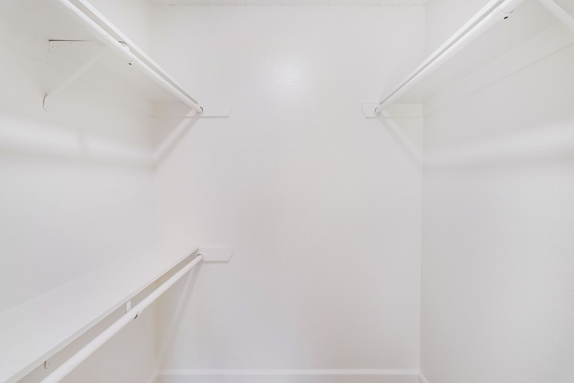 Empty white closet with shelving and a hanging rod.