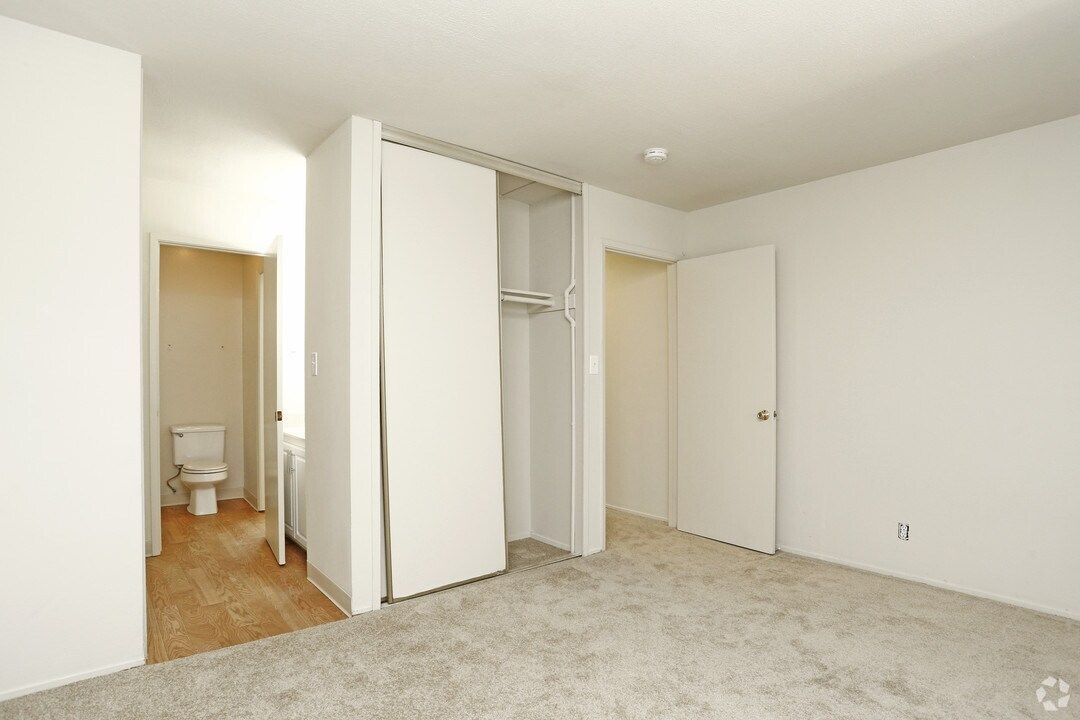 Empty bedroom with carpet, closet, and doorways to a bathroom and another room.