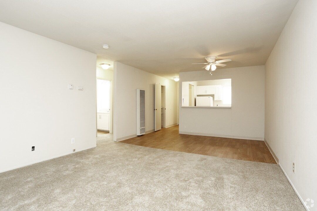 Empty apartment interior with beige carpet, light wood floors, and white walls.