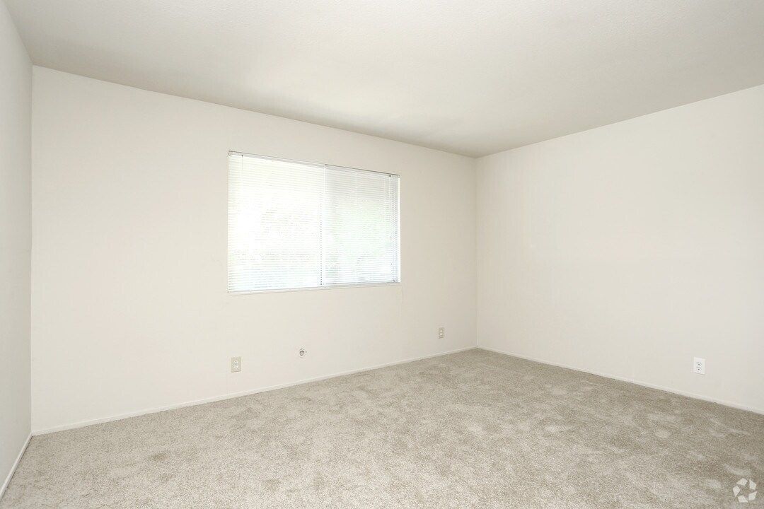Empty room with beige carpet, white walls, and a window with blinds.