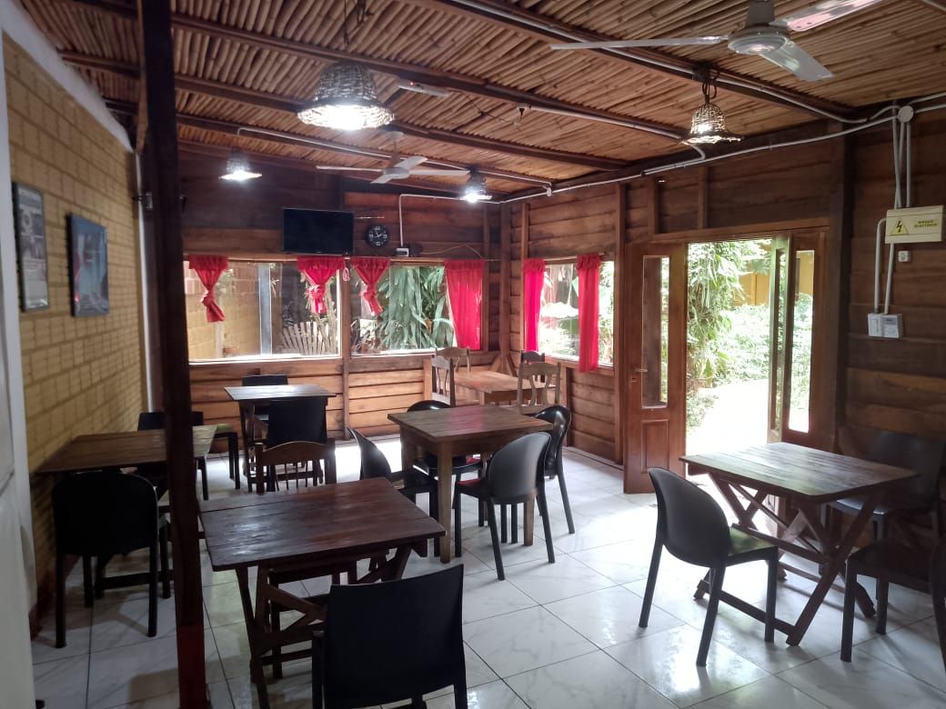 Un restaurante con mesas y sillas de madera y un ventilador de techo.