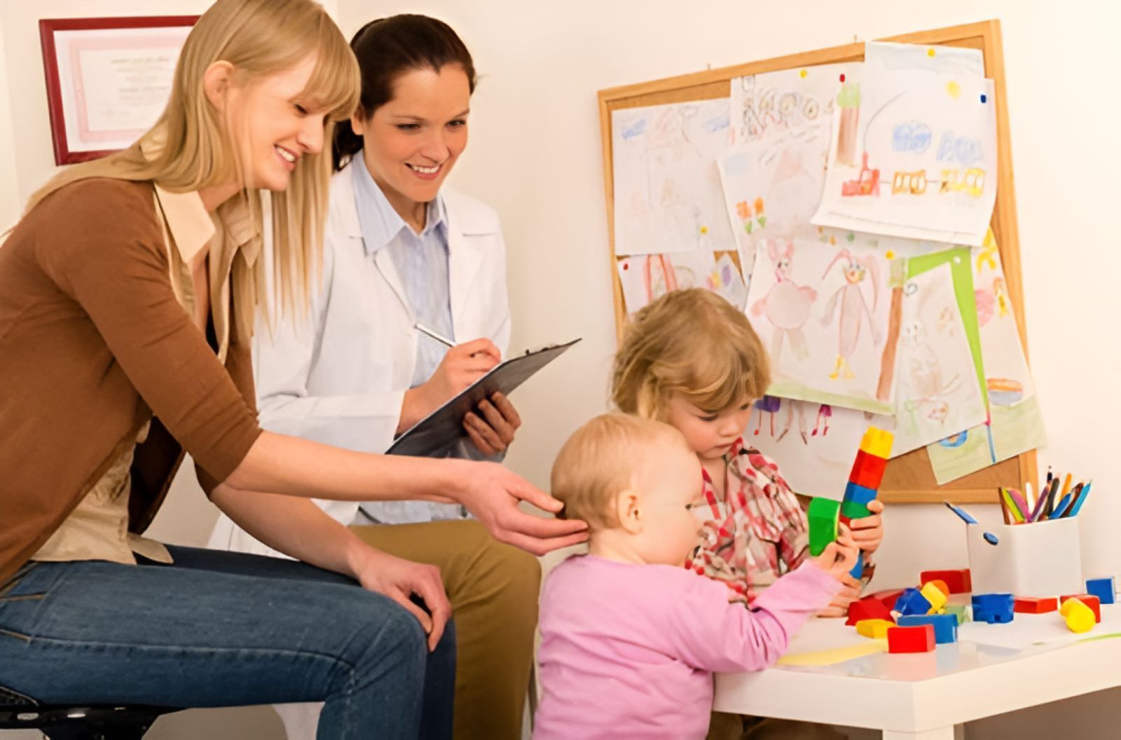 A Woman is Sitting at a Table With Two Children and a Doctor — Newcastle Paediatric Occupational Therapy in Charlestown, NSW