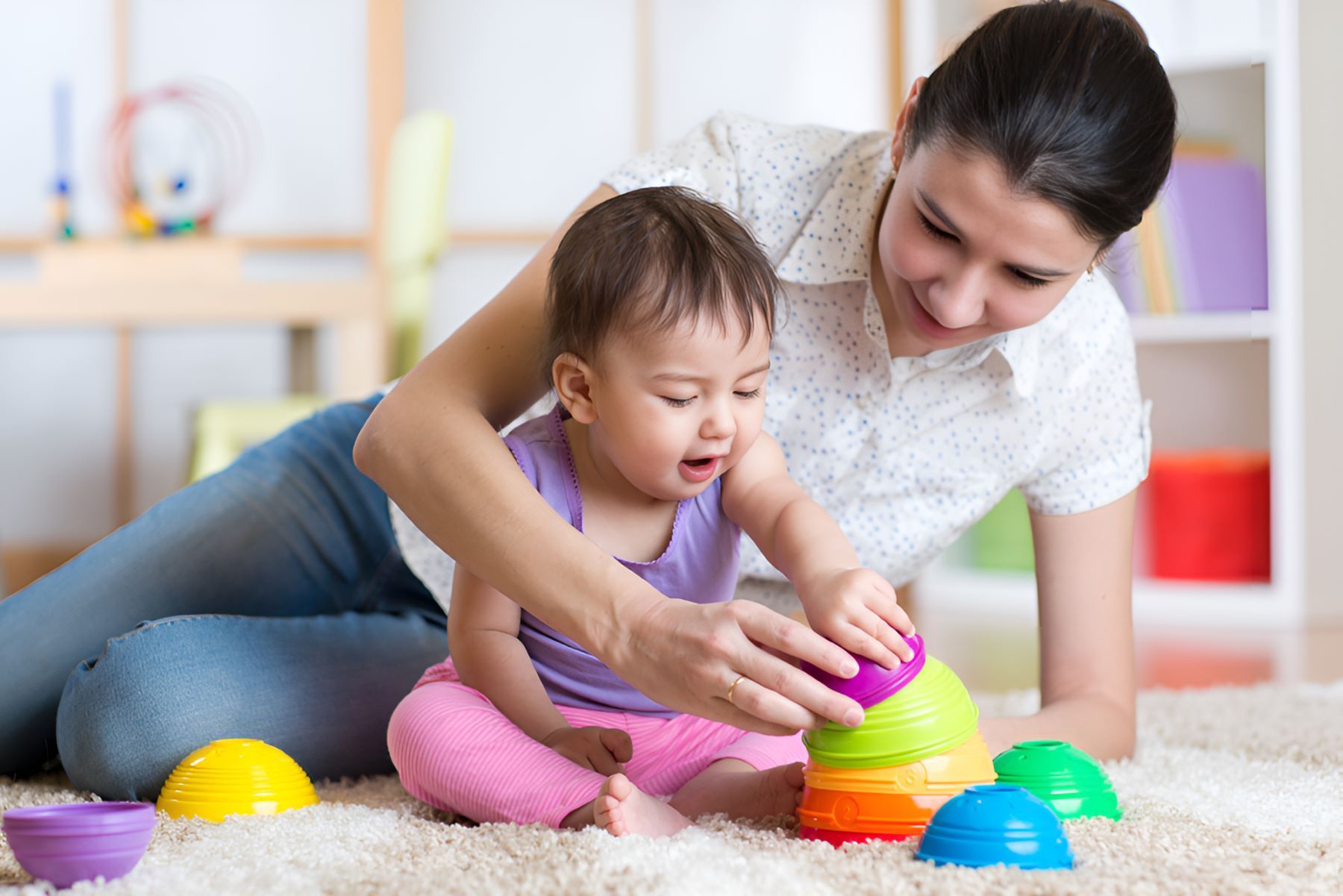 A Woman and a Baby Are Playing With Toys on the Floor — Newcastle Paediatric Occupational Therapy in Hunter Region, NSW