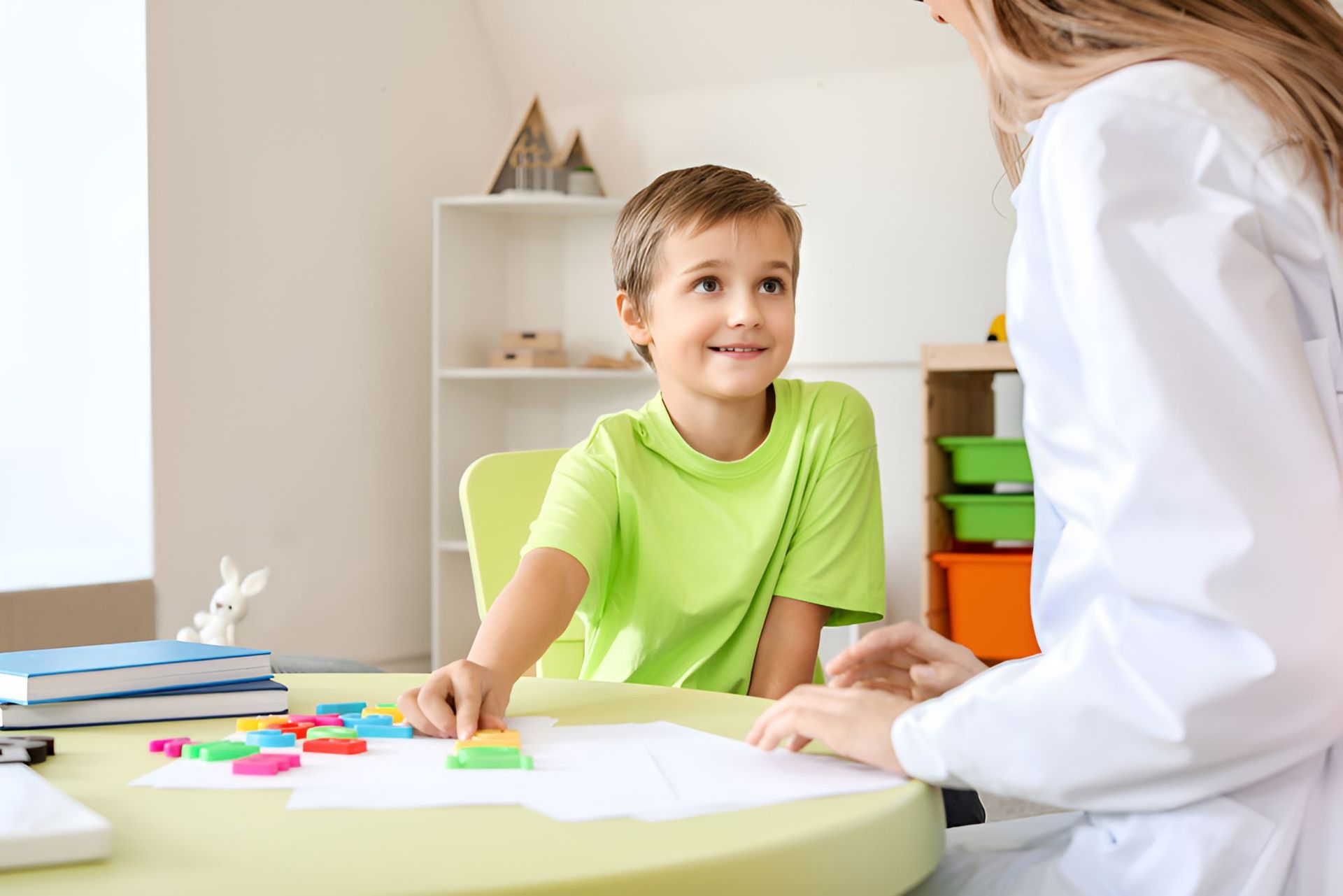 A Young Boy is Sitting at a Table Talking to a Female — Newcastle Paediatric Occupational Therapy in Lake Macquarie, NSW
