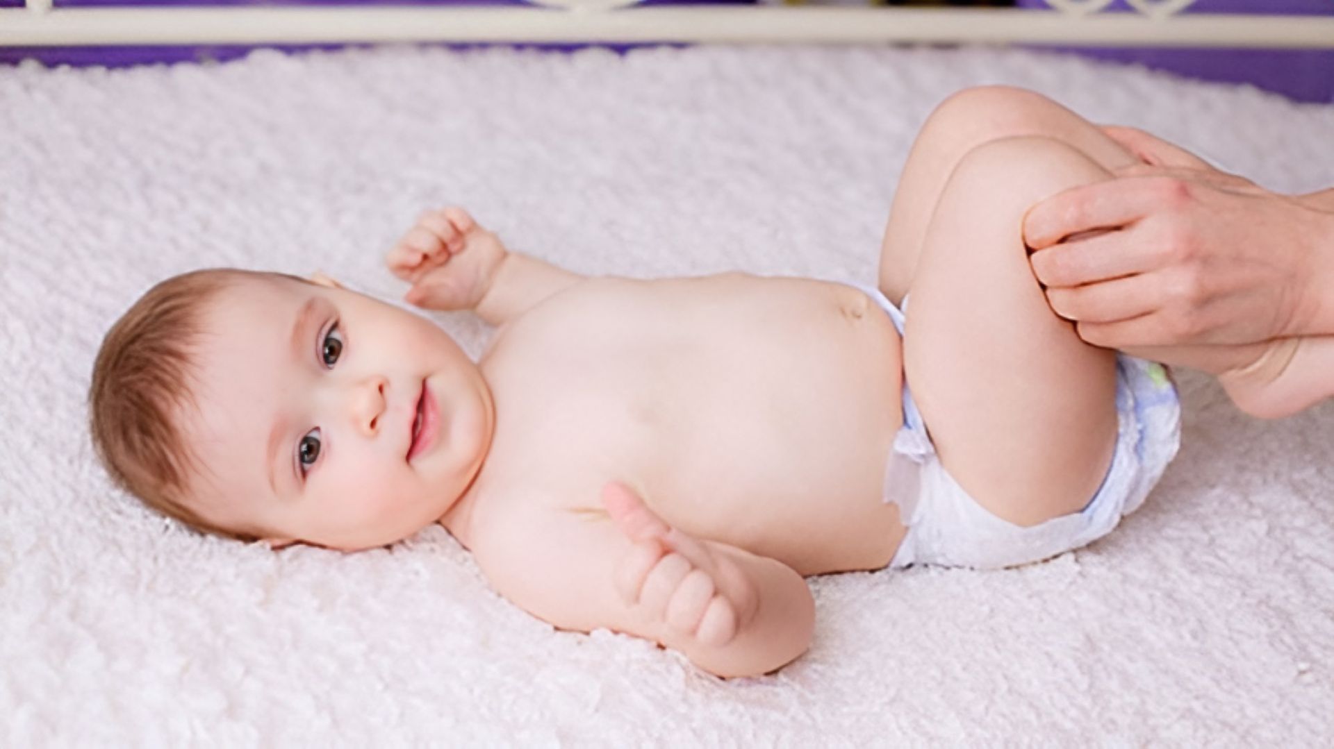 A Baby in a Diaper is Laying on a White Blanket — Newcastle Paediatric Occupational Therapy in Mayfield, NSW