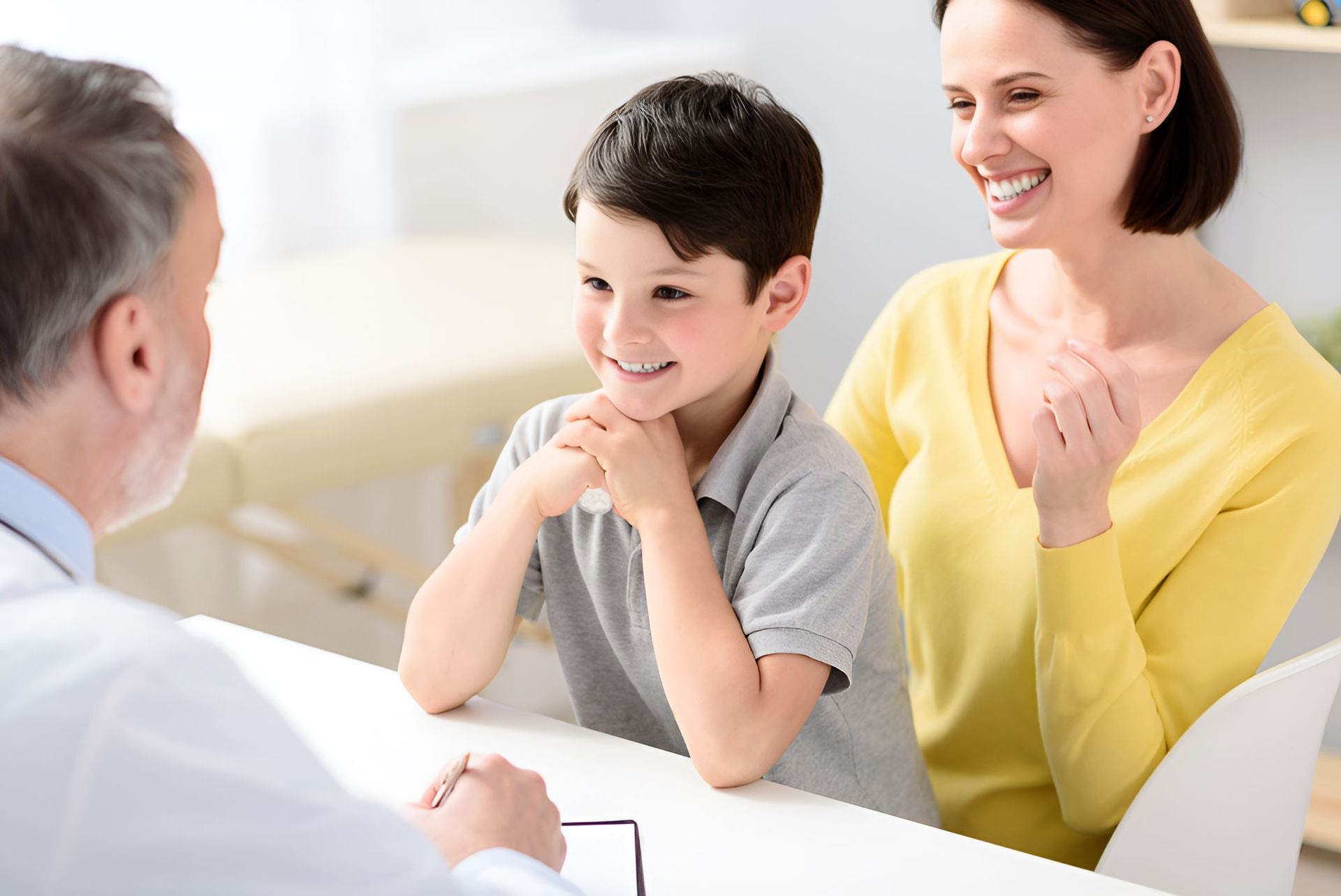 A Mother and Son Are Sitting at a Table Talking to a Doctor — Newcastle Paediatric Occupational Therapy in Newcastle, NSW