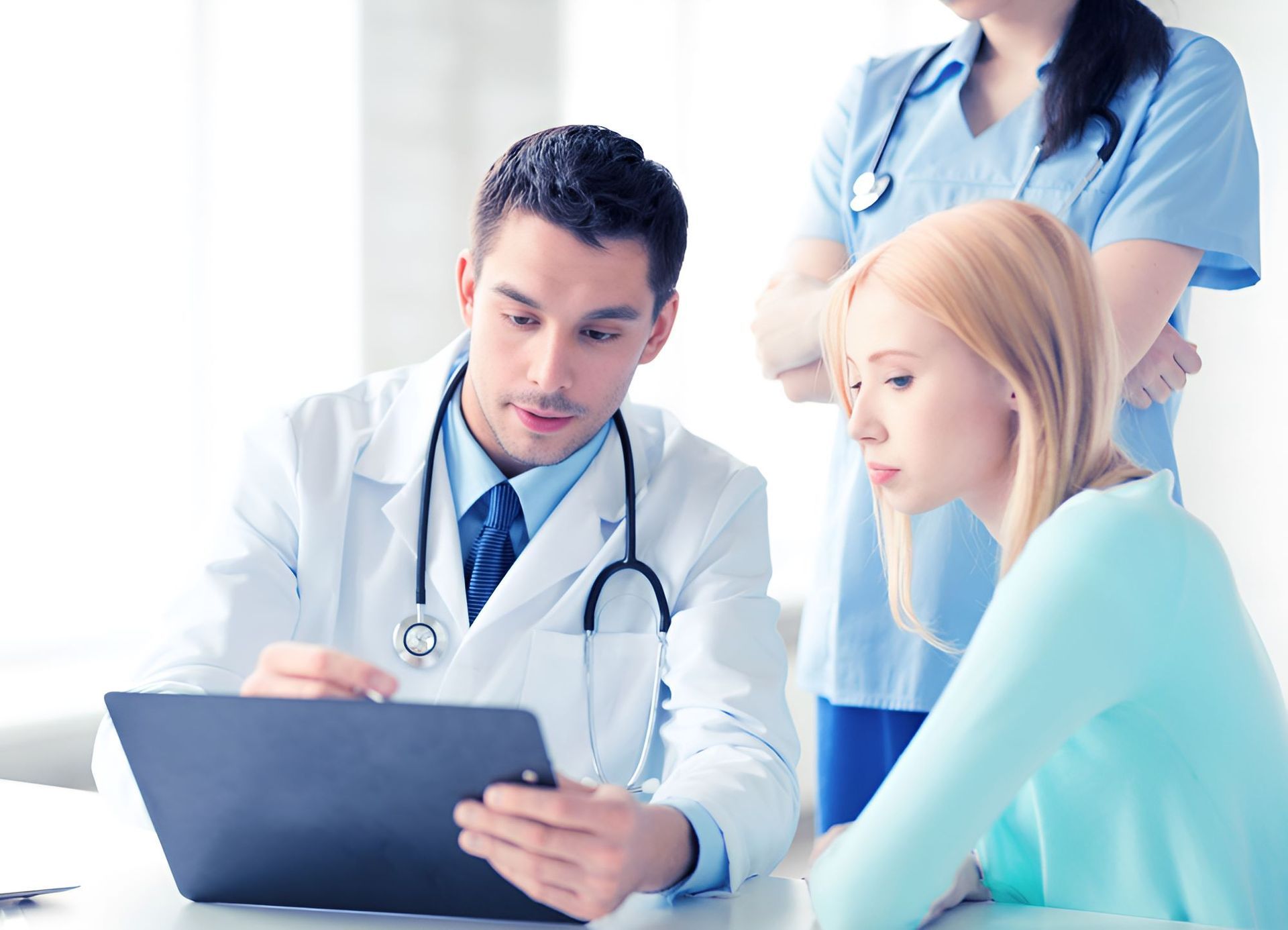 A Doctor and Nurse Are Looking at a Tablet With a Patient — Newcastle Paediatric Occupational Therapy in Newcastle, NSW