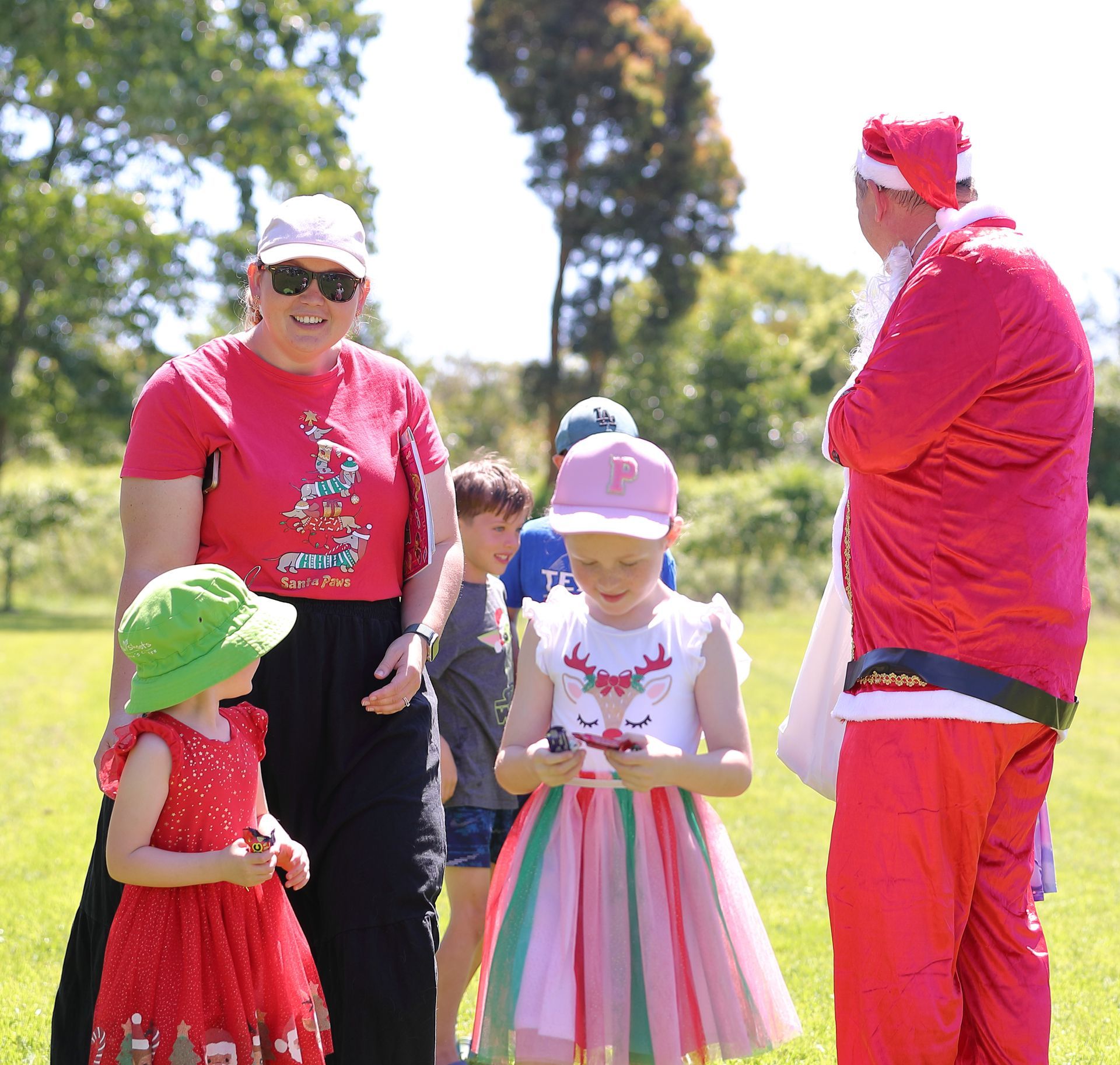 People in a park: a woman and two children with Santa.