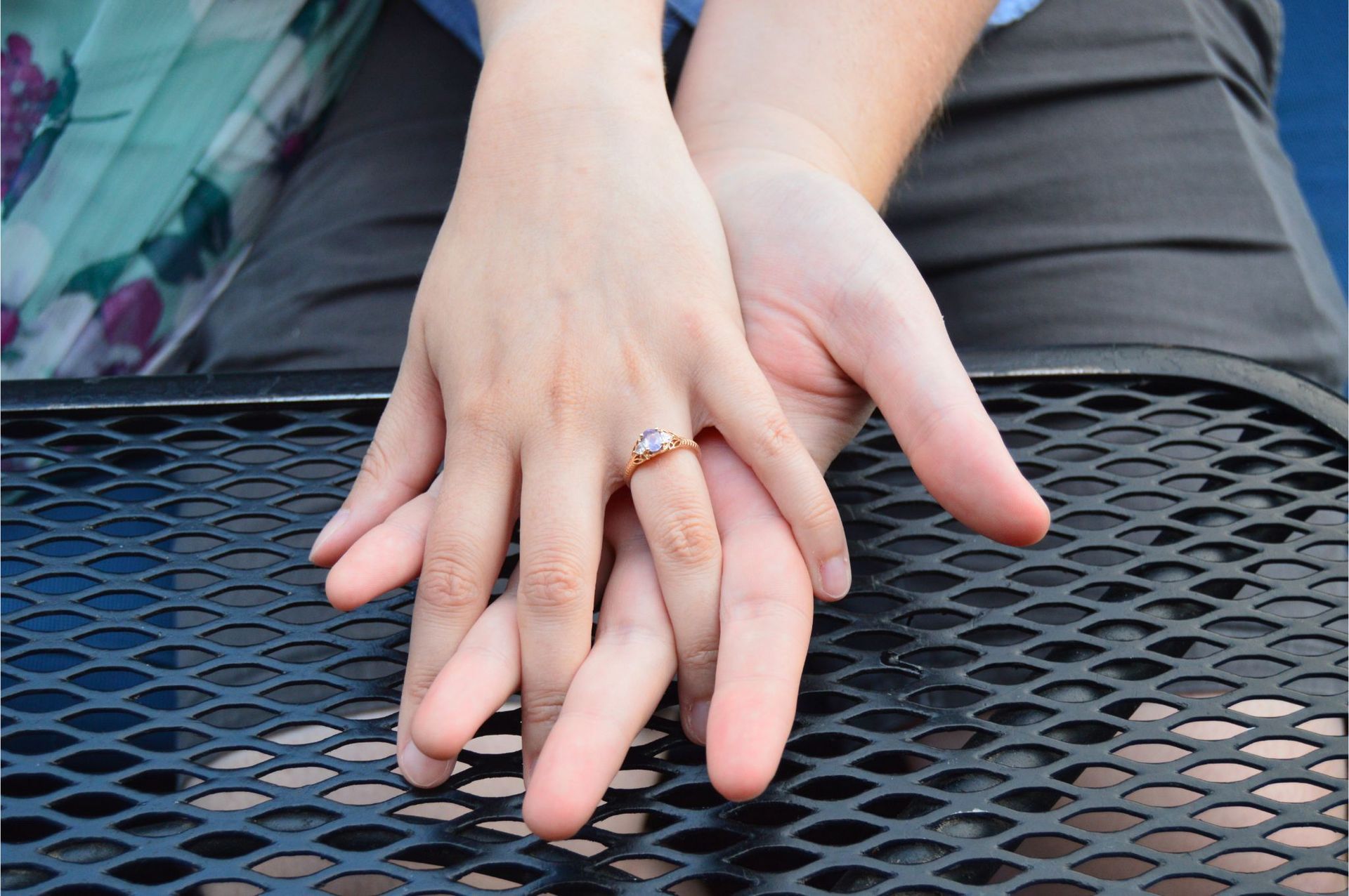 Holding hands with a lilac oval sapphire custom engagement ring.