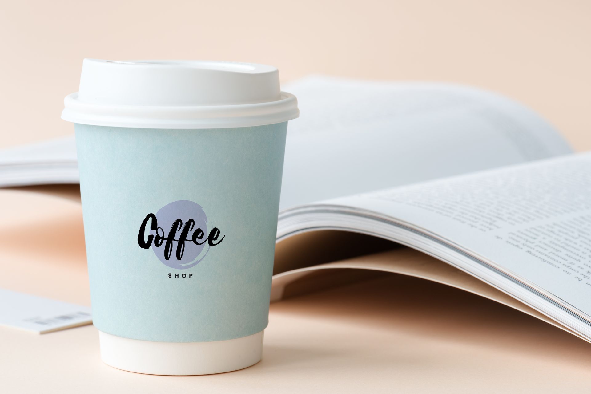 A cup of coffee is sitting next to an open book.