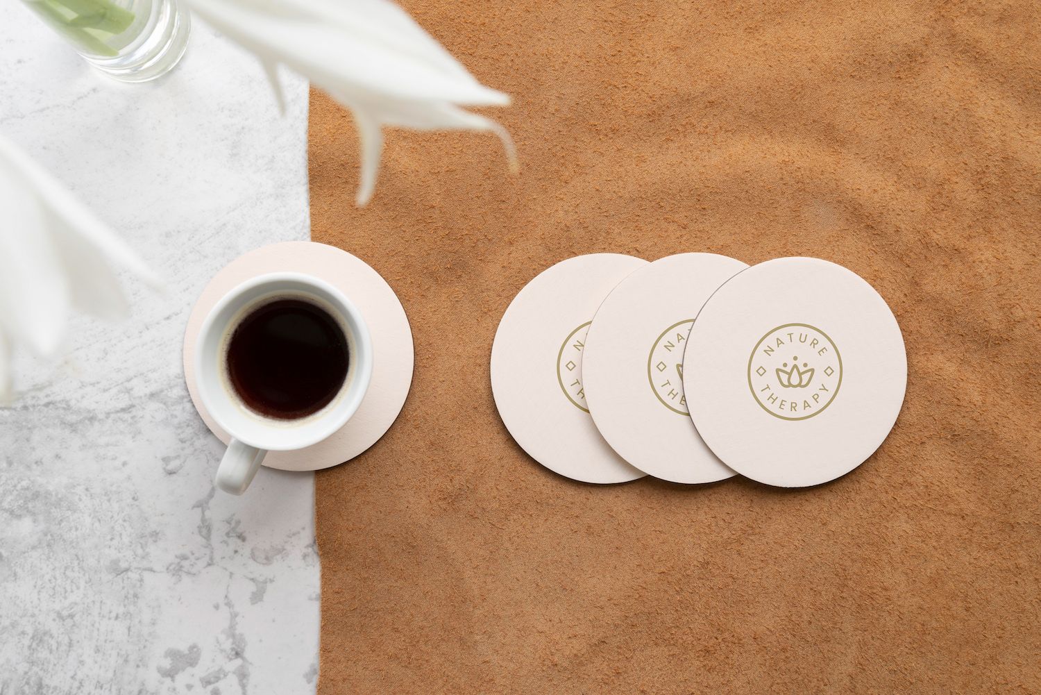 A cup of coffee and three coasters on a table.