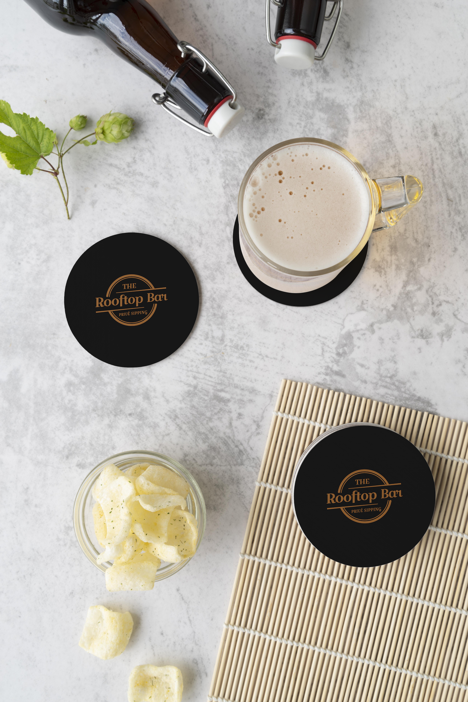 A bottle of beer , a glass of beer , and a bowl of chips are on a table.