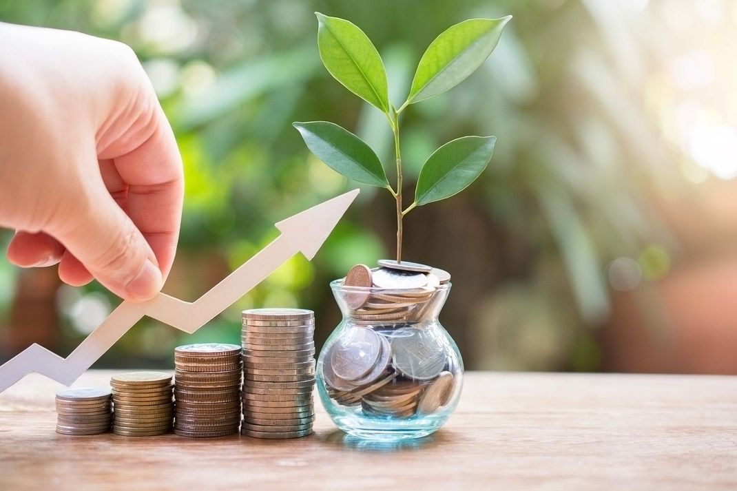 a person is holding an arrow next to a plant growing out of a vase of coins