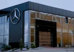 Mercedes-Benz dealership exterior with large logo and glass entrance on a cloudy day