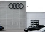 Audi dealership exterior with large four-ring logo and parked cars in front