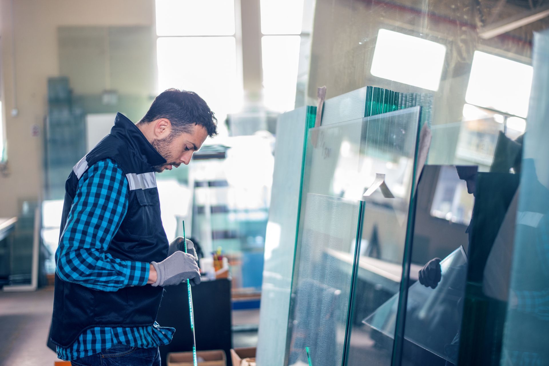 Man working with glass, wearing gloves, in a workshop.