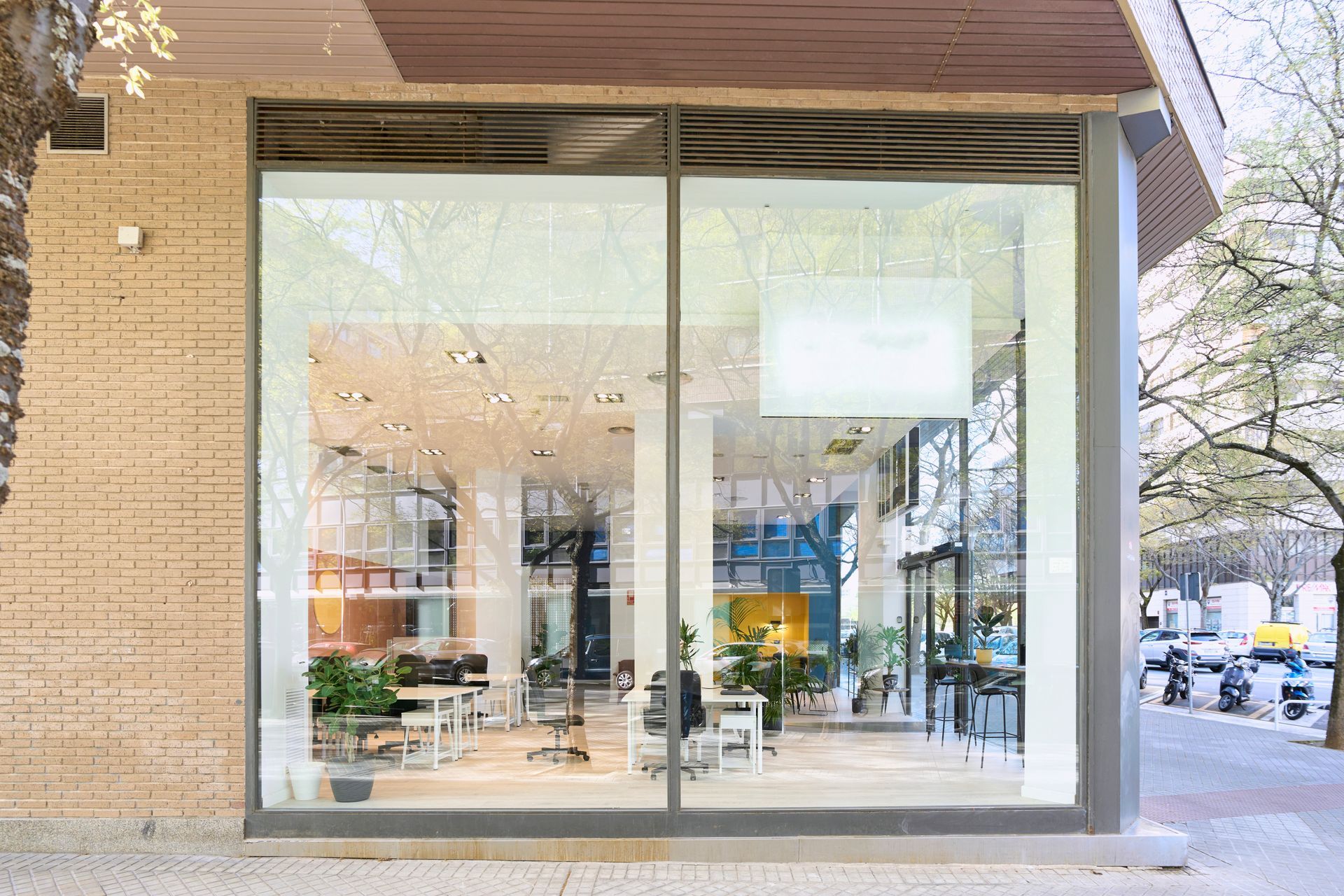 Exterior of a modern salon with large windows; interior visible, featuring chairs, tables, and plants.