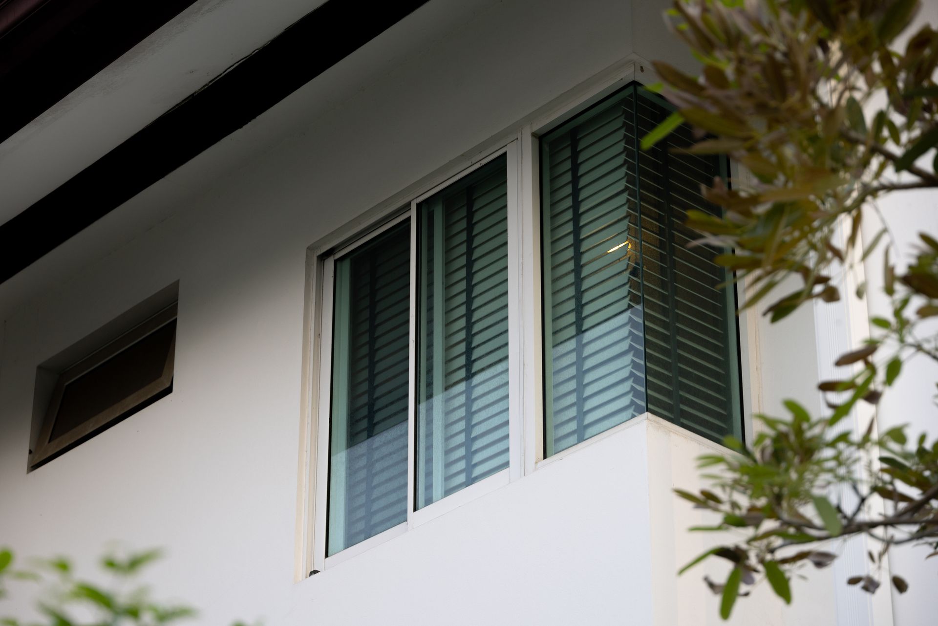 White building with large window, blinds, and a small window to the left.