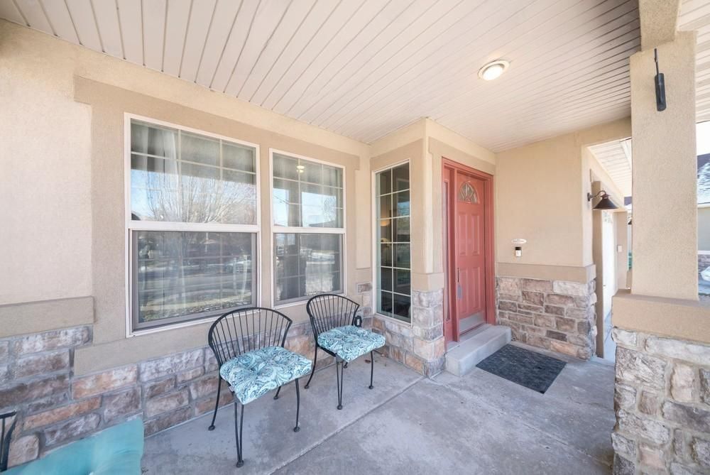 A porch with two chairs and a bench in front of a house.