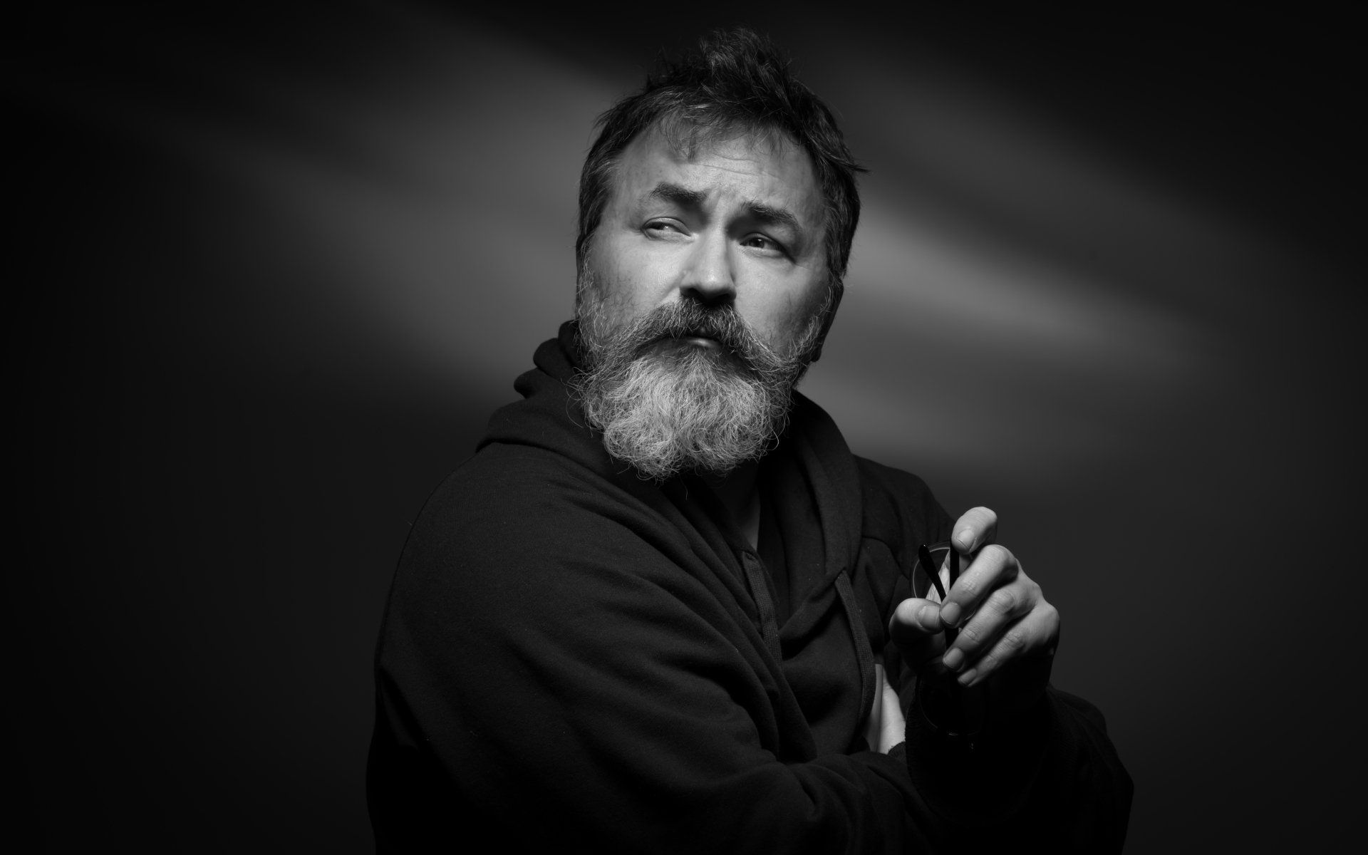 dramatic black and white portrait of  a man with a thick beard and moustache looking over his shoulder