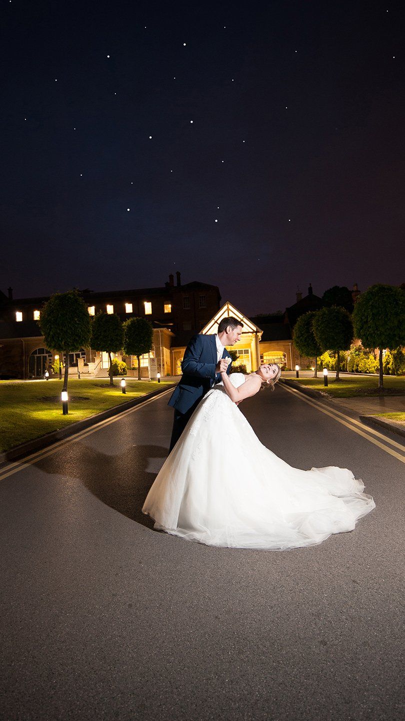 groom dips bride on driveway, with hotel entrance behind them