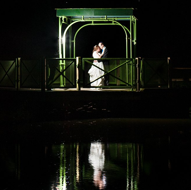 Bride and Groom embrace at the waters edge on a starlit night with their reflection in the water