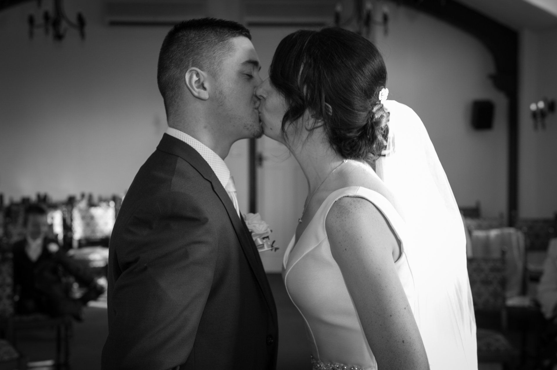 black and white image of the bride and groom having their first kiss