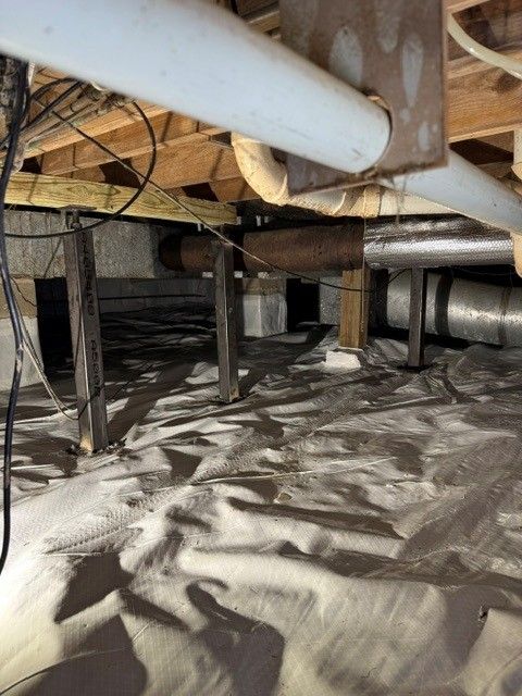 Concrete foundation of a building under construction, with steps leading down and blue pipes visible.