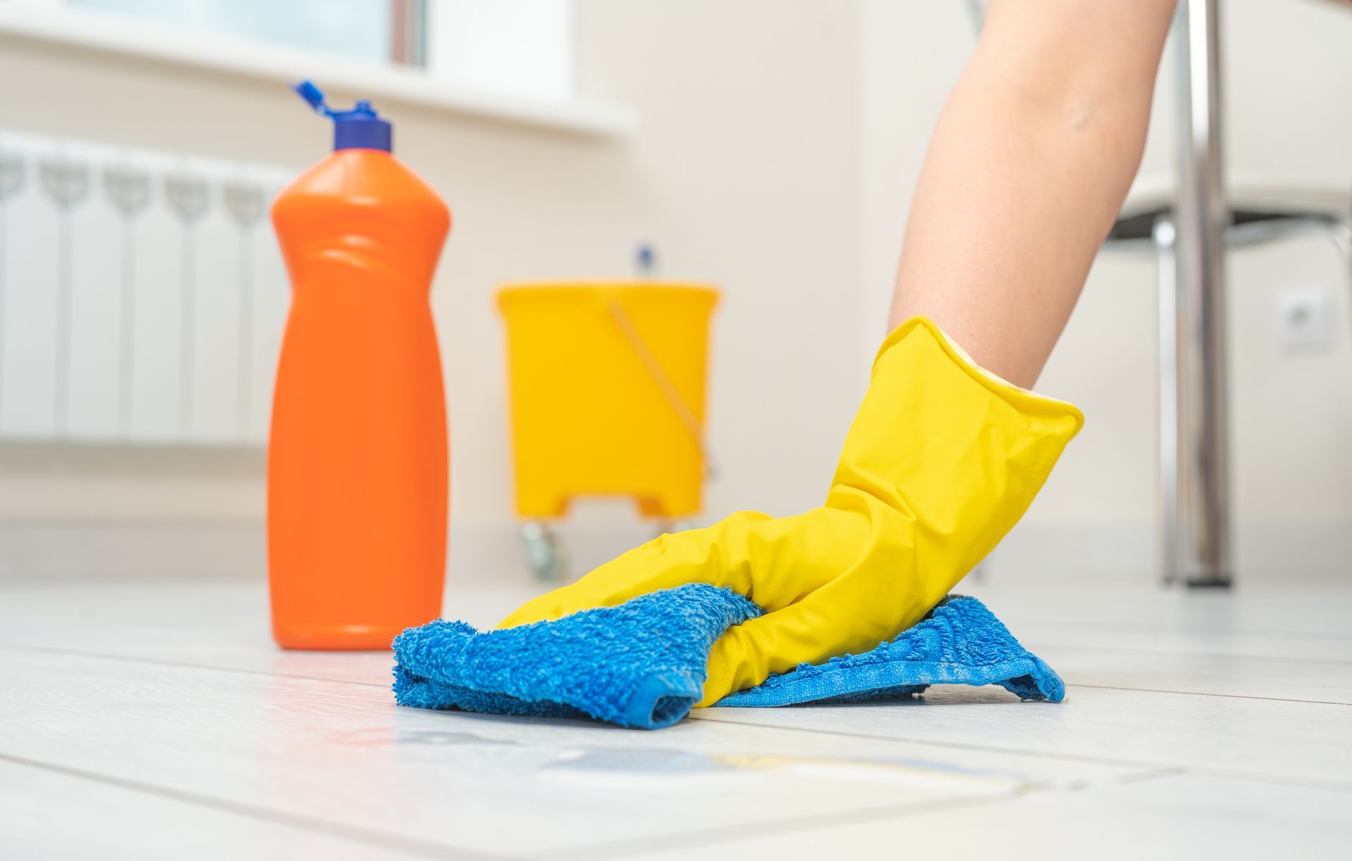 A woman wearing gloves cleaning the floor.