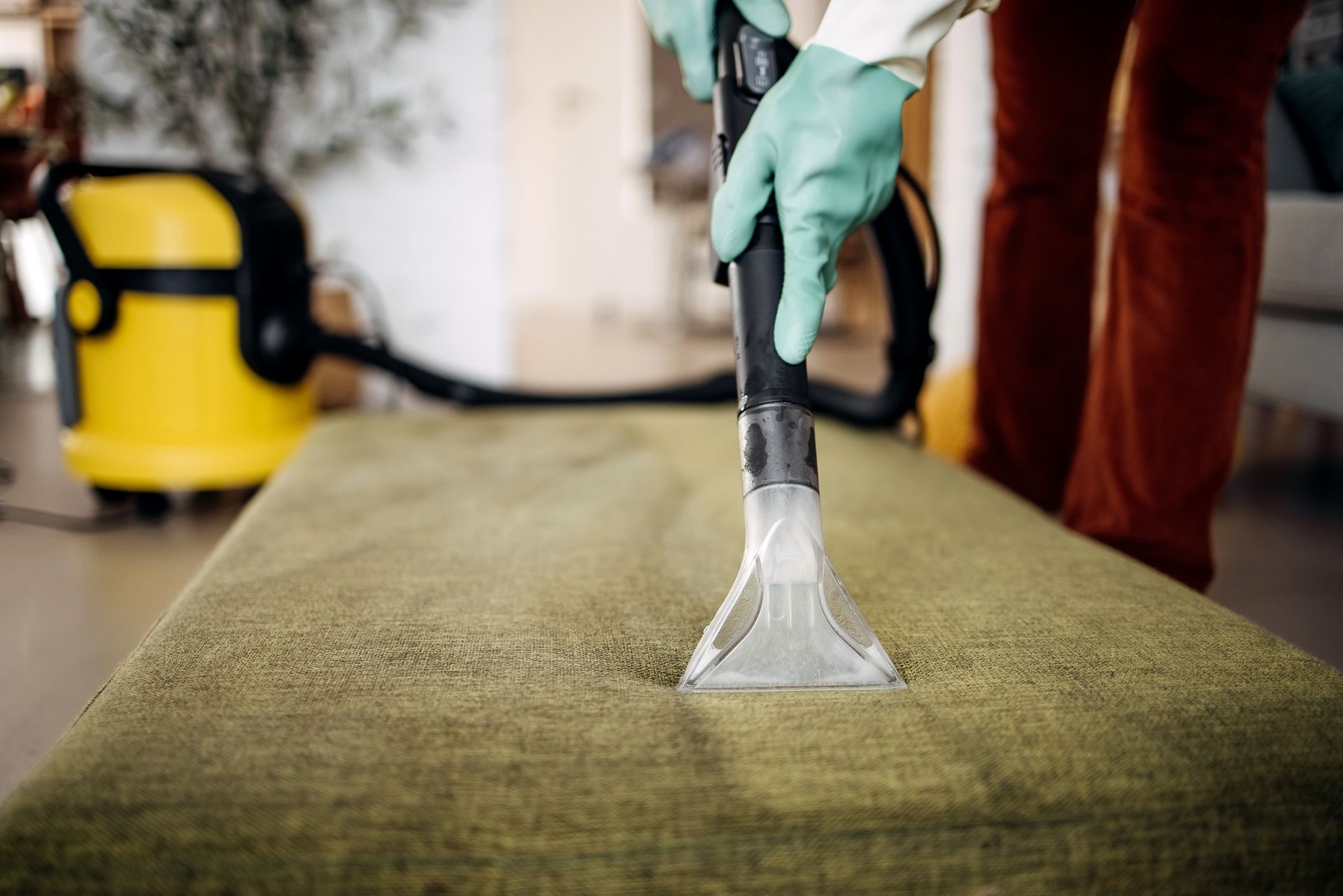 Individual cleaning a couch with a vacuum, representing Majestic Domestics' One-Time Deep Cleaning 