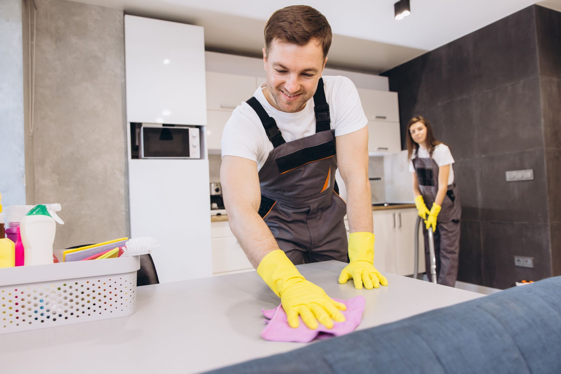 Cleaning company employees are cleaning a kitchen table and floor.