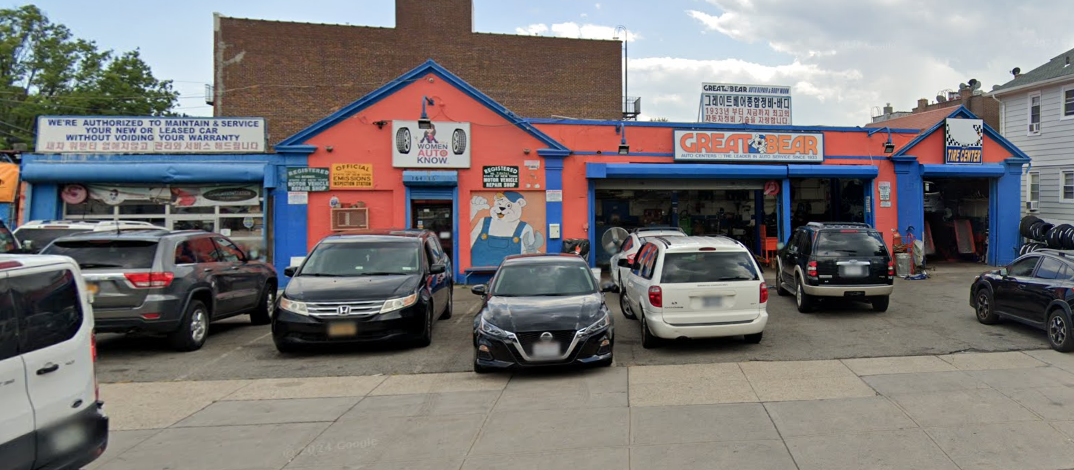 A man is talking on a cell phone while standing next to a car.
