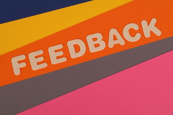 “FEEDBACK” text in white on an orange and dark gray diagonal banner over pink background