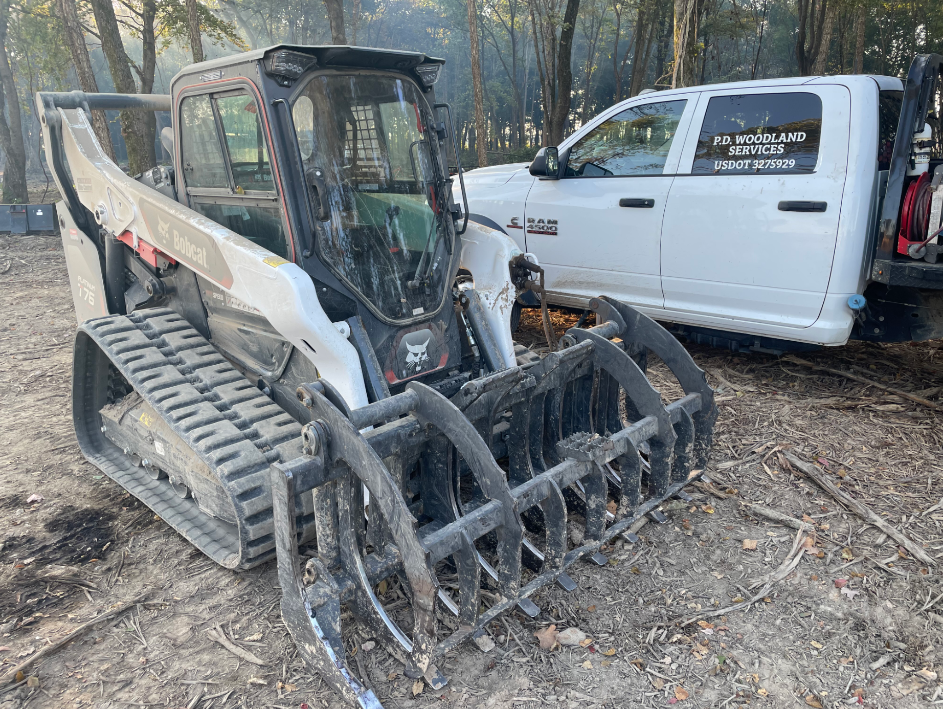 A bulldozer is parked next to a white truck.